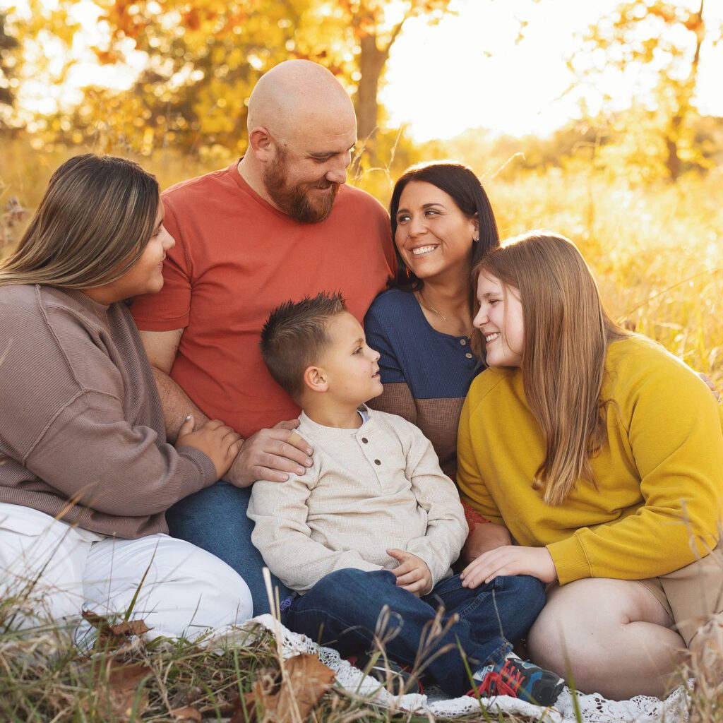 Family sitting together in a field during golden hour fall family photo in Kansas City