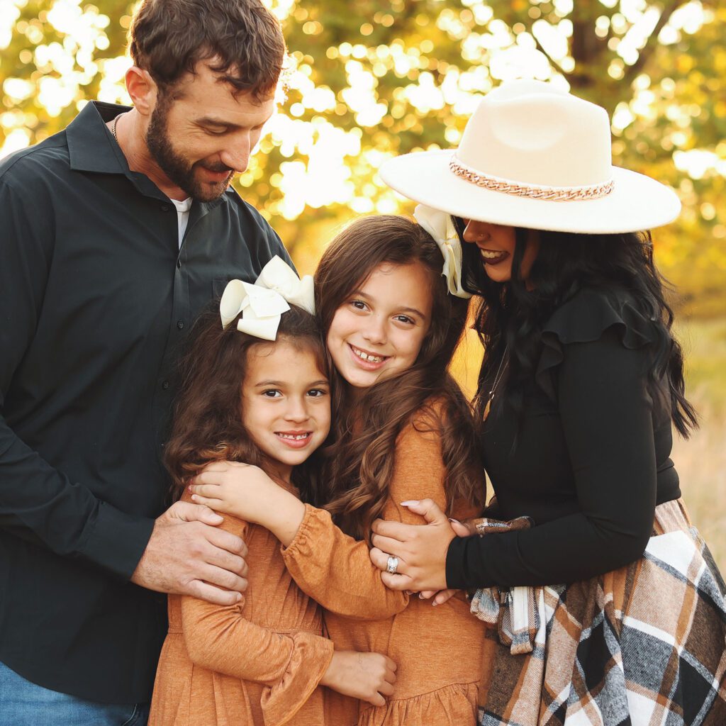 Parents watching their daughters hug during a fall golden hour family session