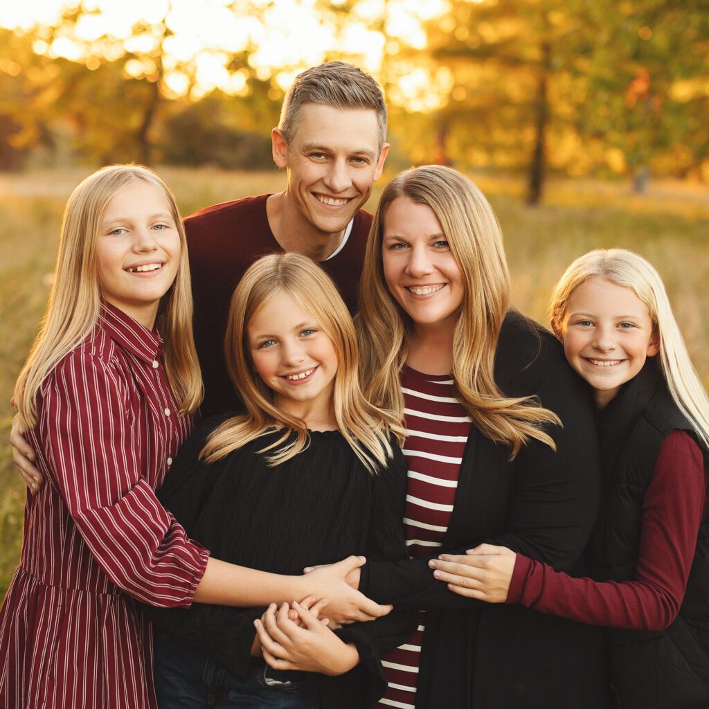 Family with three daughters posing together durina fall outdoor session