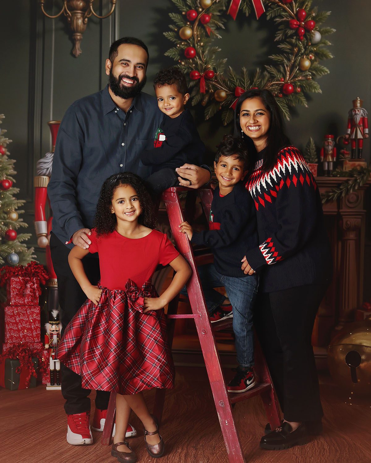 Family smiling together during a Christmas photo session with children climbing a ladder