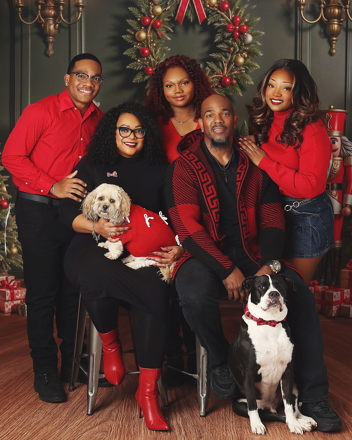 Family Christmas portrait with parents, children, and two dogs in a festive holiday setting.