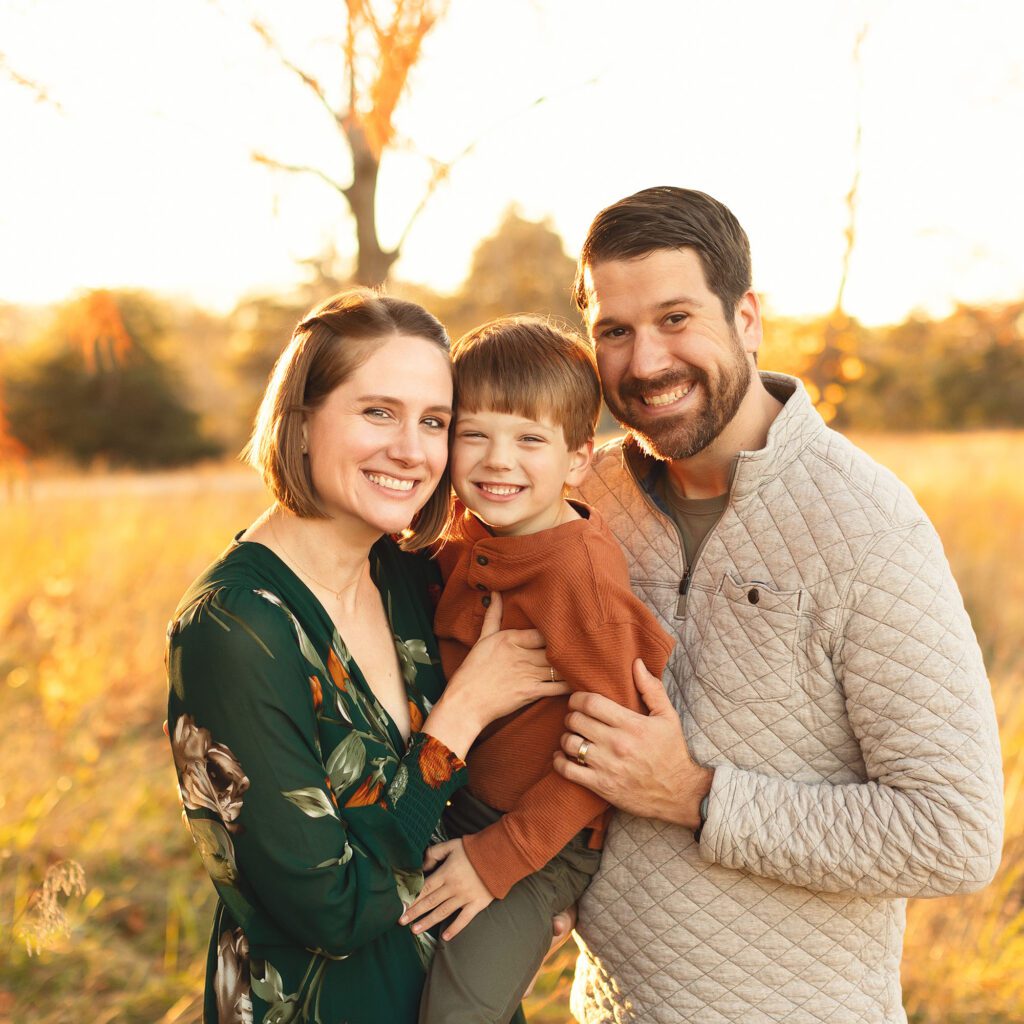 Parents hugging their young son during a fall outdoor family session
