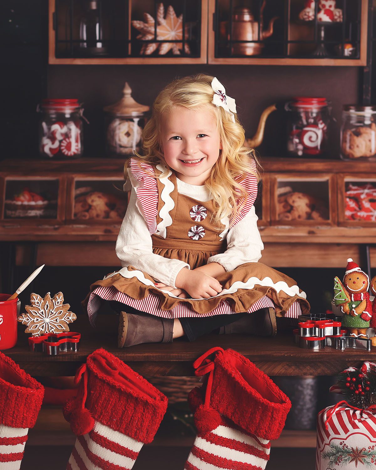 Little girl in a gingerbread dress sitting with baking supplies during a Christmas photography session.