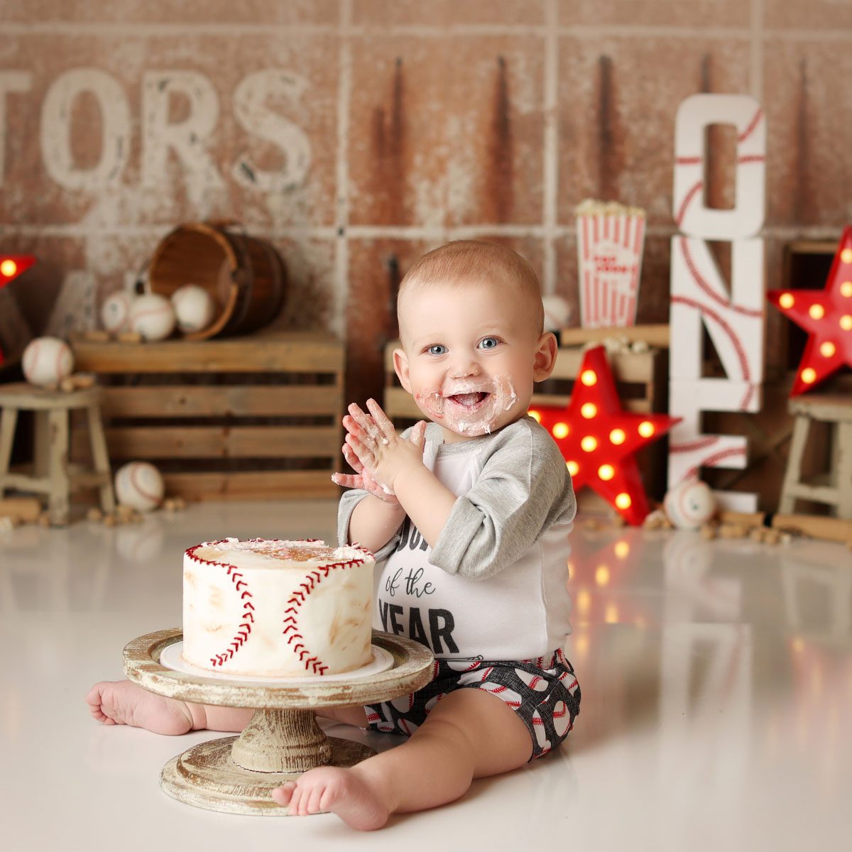 Little boy clapping during baseball themed cake smash with baseball cake in Kansas City