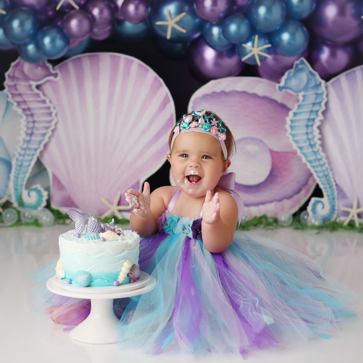 Little girl clapping during purple and blue mermaid theme cake smash in Kansas City