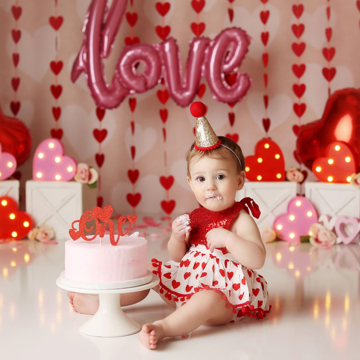 Little girl valentine theme cake smash session in Kansas City with pink and red decor