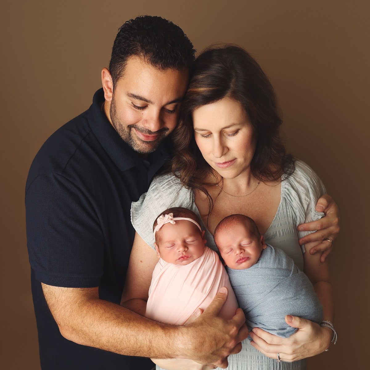 Parents holding their newborn twins, a baby boy and a baby girl, during a studio newborn photography session in Kansas City