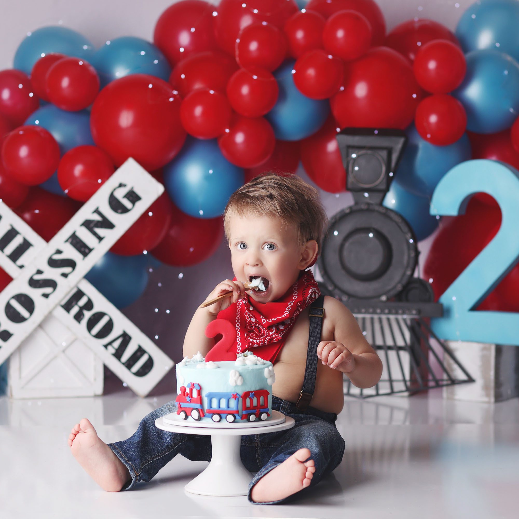 Kansas City, MO train themed cake smash for two year old boy in blue and red decor with bandana