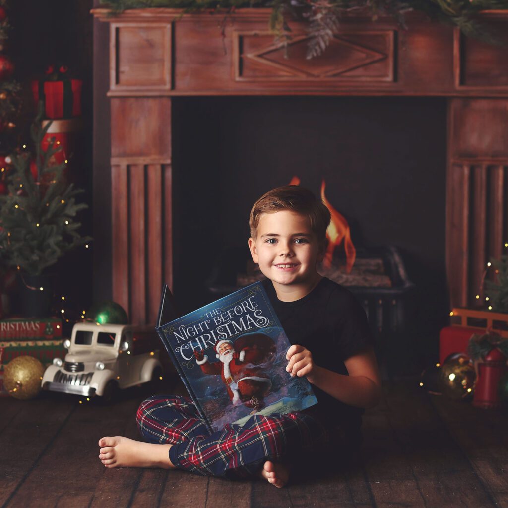 Young boy in plaid Christmas pajamsas holiding the night before Christmas book