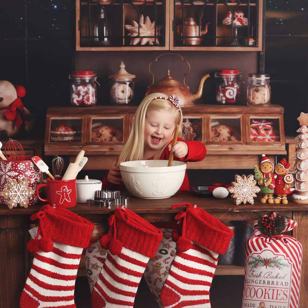 Little girl stirring a bowl and smiling in a Christmas kitchen photo set up