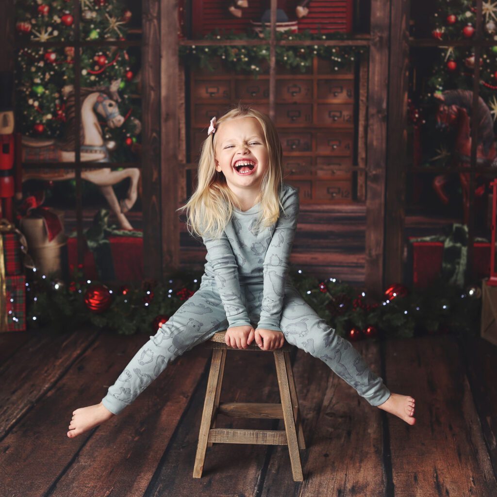 Little girl kicking her feet and laughing in Christmas pajamas