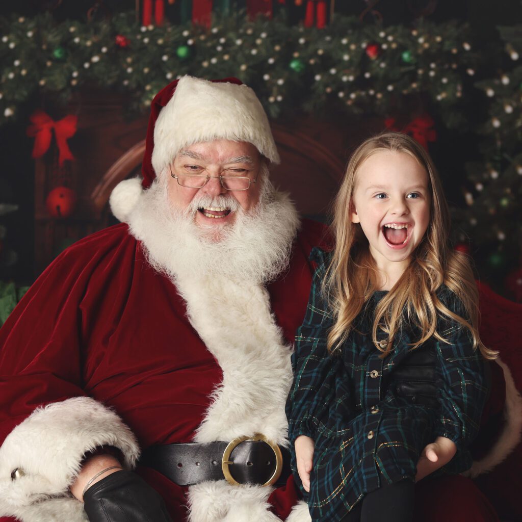 Santa and little girl laughing together during a Christmas photo session