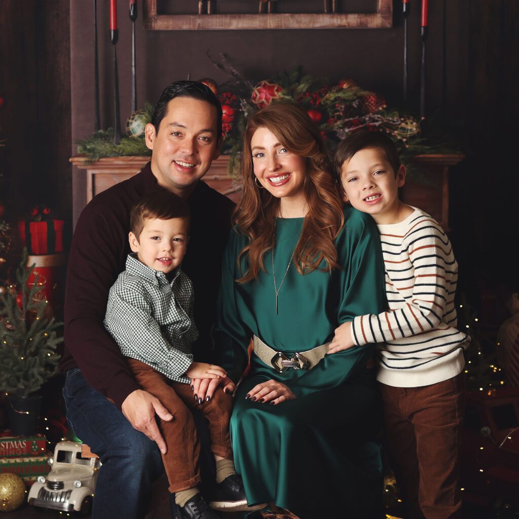 Parents with two young sons posing together in Christmas room set up