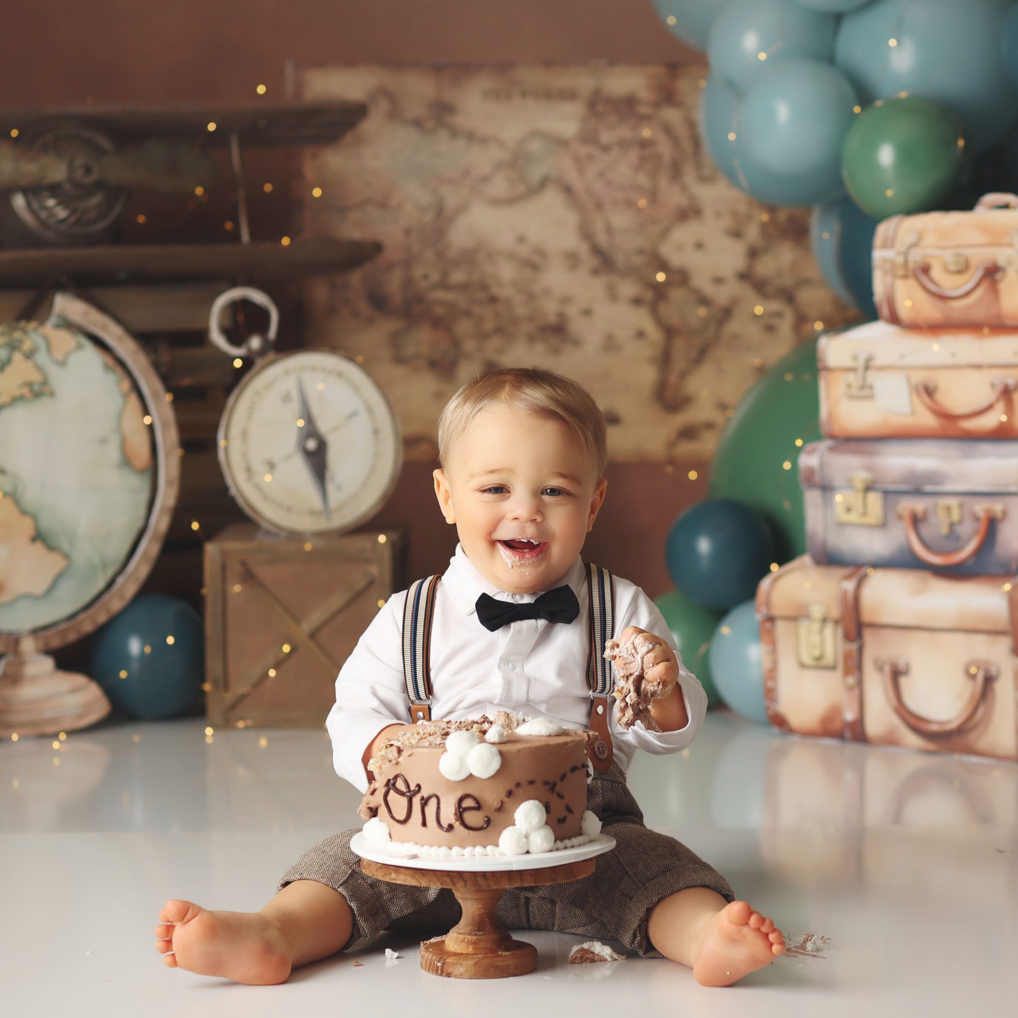 Baby boy cake smash session with world traveler theme and suitcases in Olathe Kansas studio