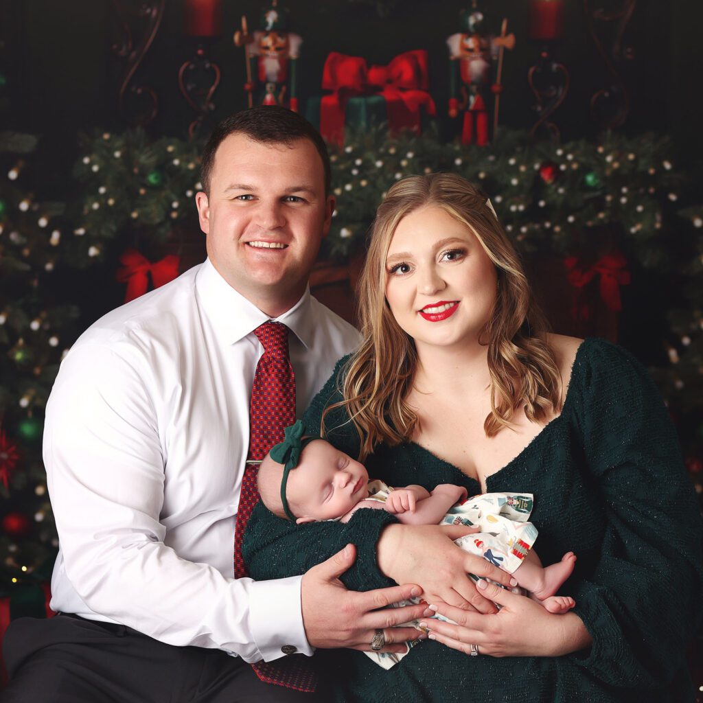 Parents holding their sleeping newborn daughter in a Christmas studio set up