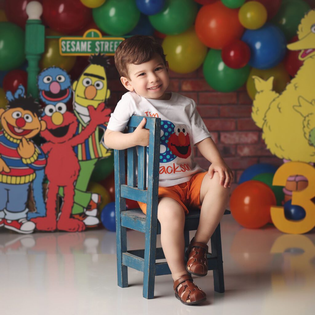 Three year old boy smiling in a Sesame Street themed birthday studio portrait
