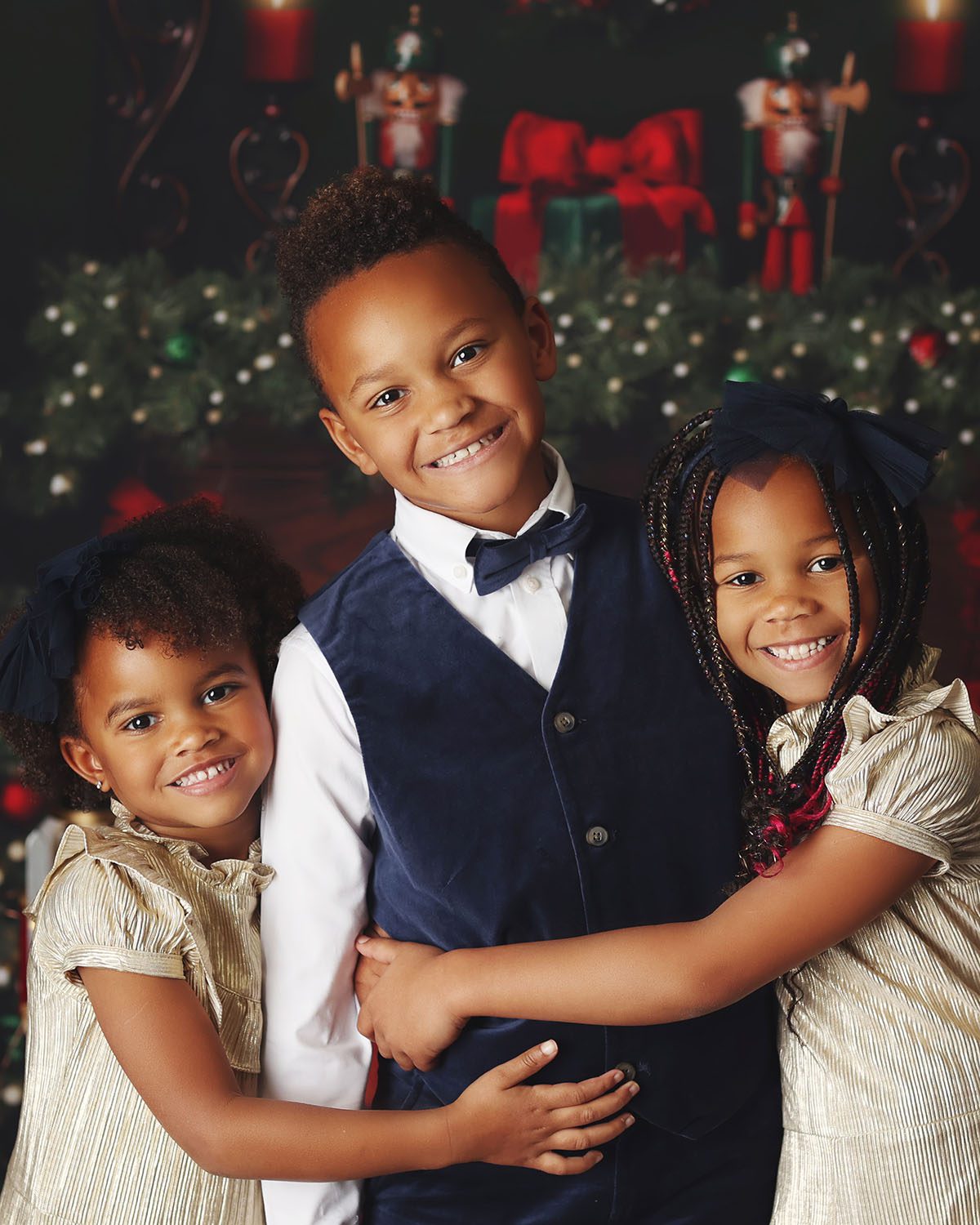 Three siblings hugging during a Christmas photo session with a festive holiday backdrop.