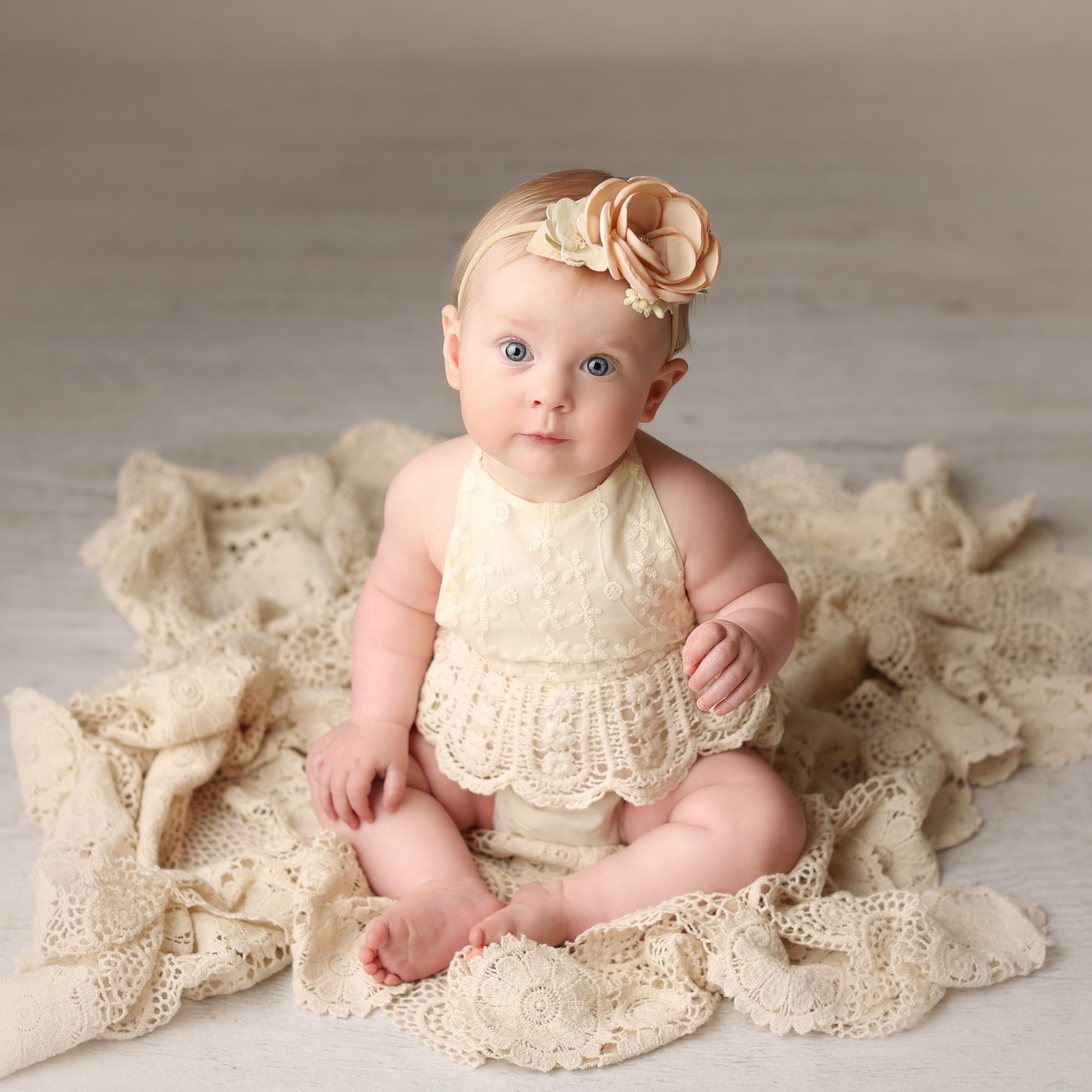 Kansas City, MO baby girl sitter session wearing lace romper sitting on knit blanket with bow