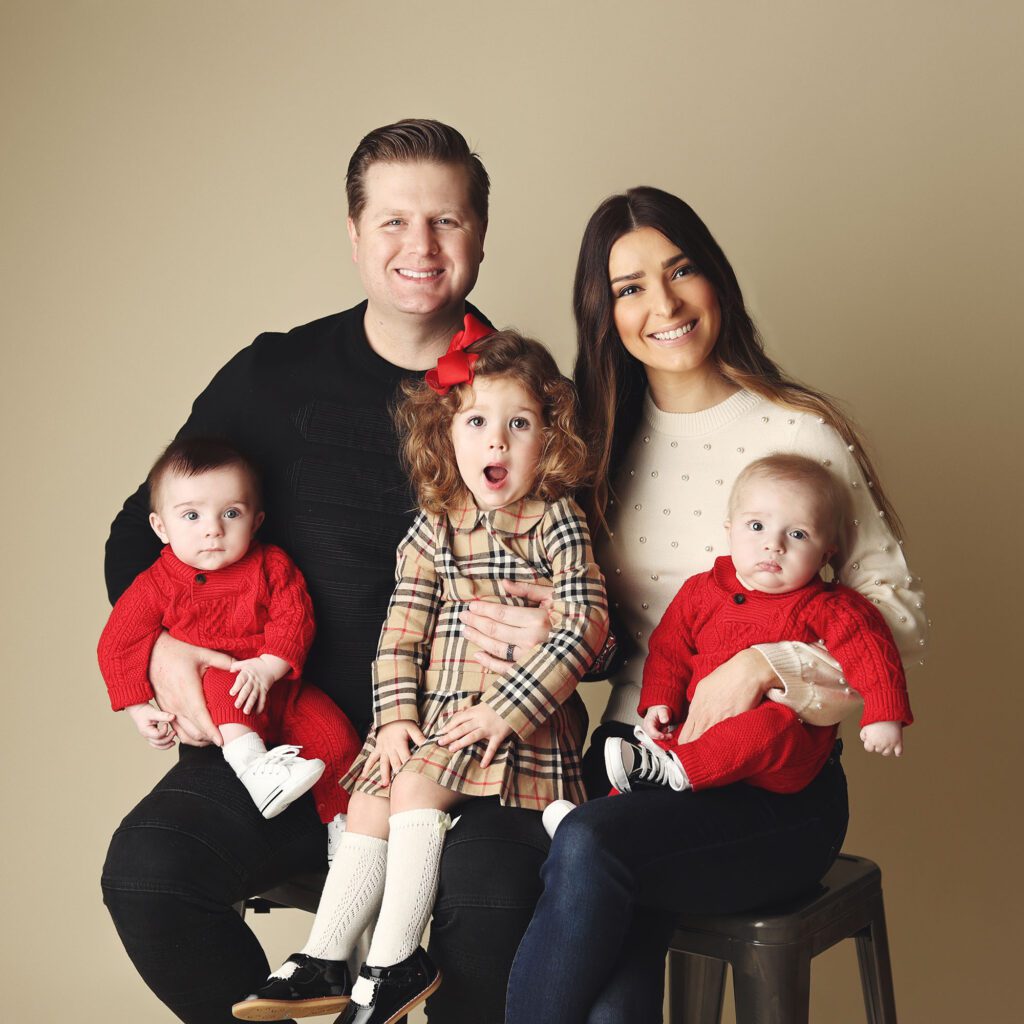 Parents holding infant twin boys with toddler daughter during a studio family portrait
