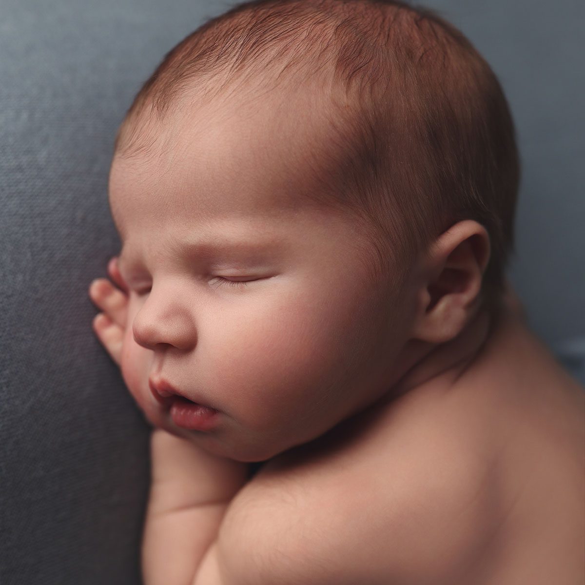 Close up profile of a newborn baby boy resting on a blue blanket during a Kansas City newborn photography session