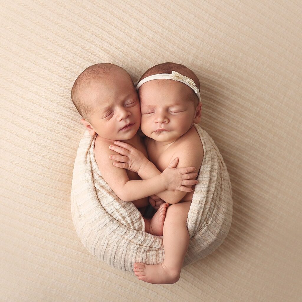Twin newborns posed cheek to cheek on a neutral blanket during a studio newborn photography session near Lee's Summit