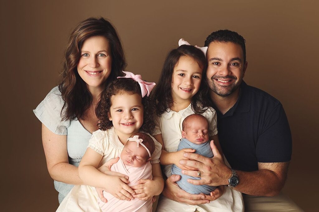 Family portrait during a twin newborn photography session near Lee's Summit with parents, two older sisters, and newborn boy girl twins.
